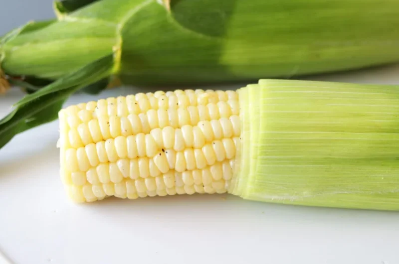 Microwave corn on the cob on a white plate.