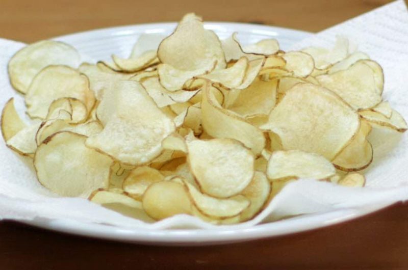 white plate with paper towel and thin crispy potato chips