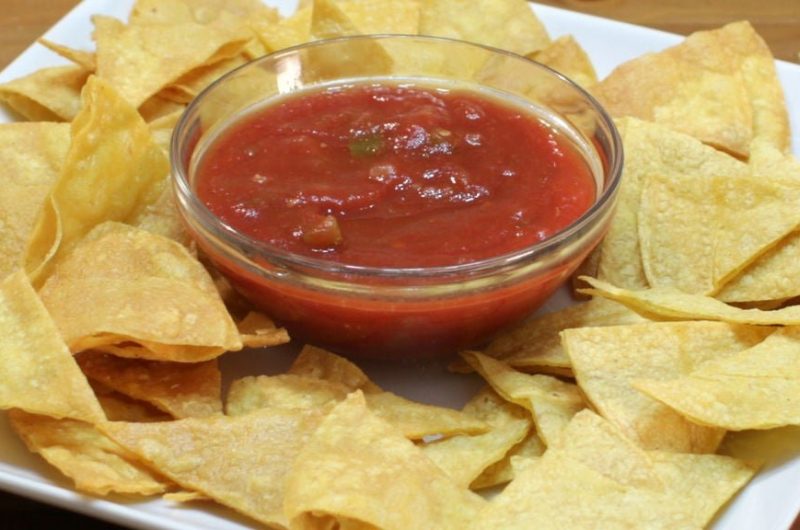 homemade tortilla chips on a white plate with salsa
