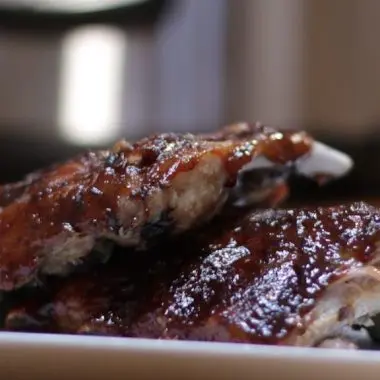 2 racks of baby back ribs covered in bbq sauce on a white plate