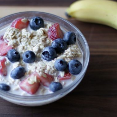 glass bowl full of overnight oats with strawberries and blueberries