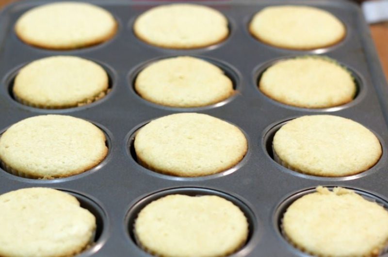 homemade vanilla cupcakes in a gray cupcake pan on wooden table