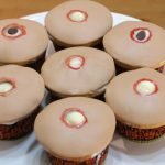 7 cupcakes with tan fondant and holes that look like pimples