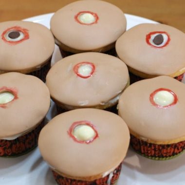 7 cupcakes with tan fondant and holes that look like pimples