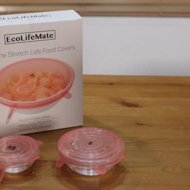 two glass bowls sitting on a wooden table with silicone stretch lids