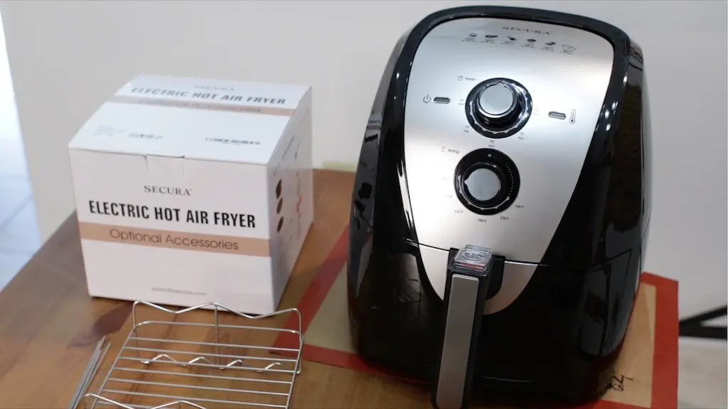 Secura Air Fryer sitting on a wooden table next to a box of air fryer accessories.