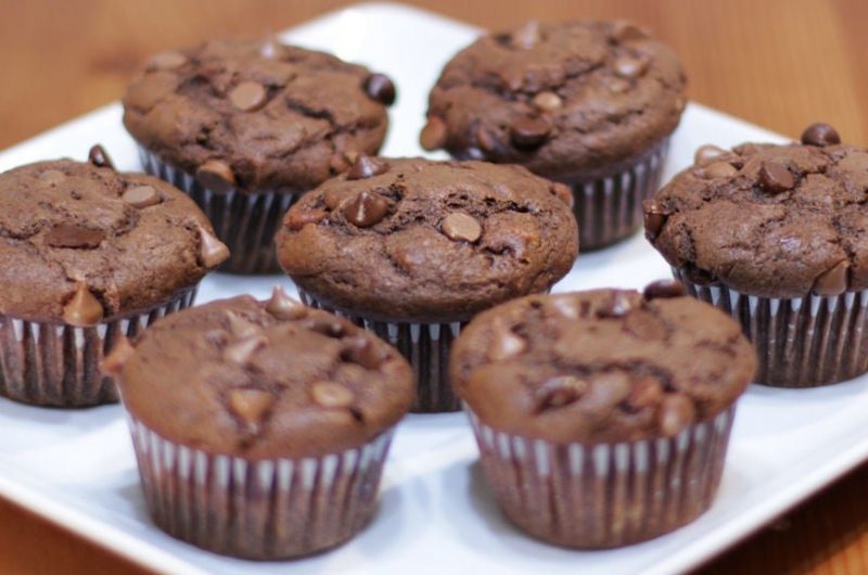 7 chocolate banana muffins on a white plate on a table