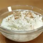 Glass bowl of rice pudding topped with cinnamon