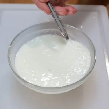 homemade buttermilk in a glass bowl on a white cutting board