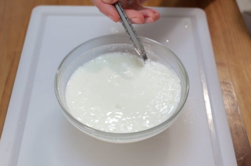 homemade buttermilk in a glass bowl on a white cutting board
