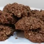 several no-bake chocolate oatmeal cookies piled on a white pedestal