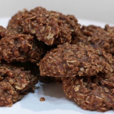 several no-bake chocolate oatmeal cookies piled on a white pedestal
