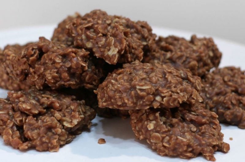 several no-bake chocolate oatmeal cookies piled on a white pedestal