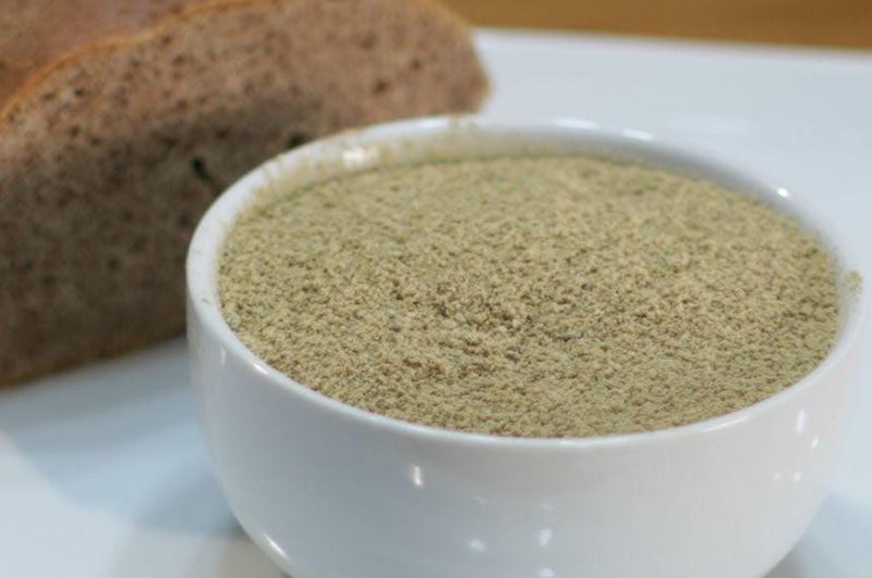 white bowl holding processed acorn flour next to acorn bread
