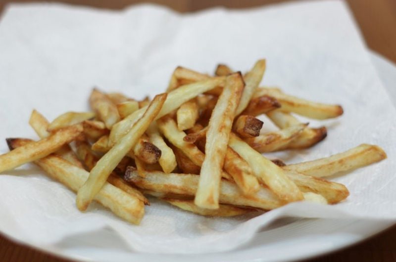 Easy crispy air fryer french fries on a white paper towel on a white plate