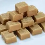 Peanut butter fudge cut in cubes stacked on a white plate