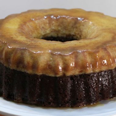 Chocoflan recipe cake on a white cake pedestal on wooden table