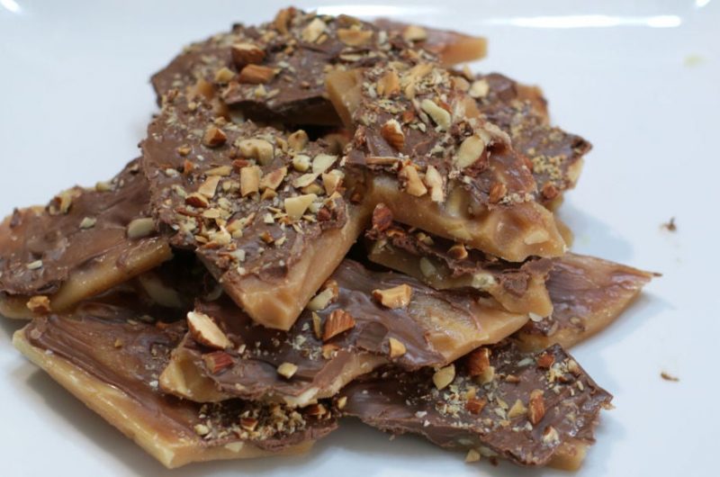 homemade almond roca piled up on a white plate