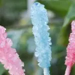 homemade rock candy with green plants behind it.