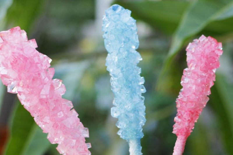 homemade rock candy with green plants behind it.