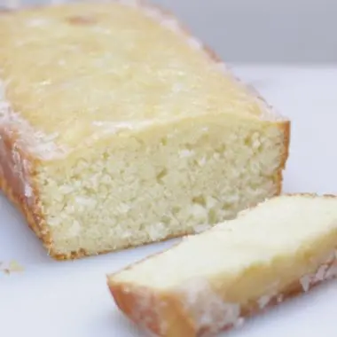 coconut bread on a white cutting board on top of a wooden table