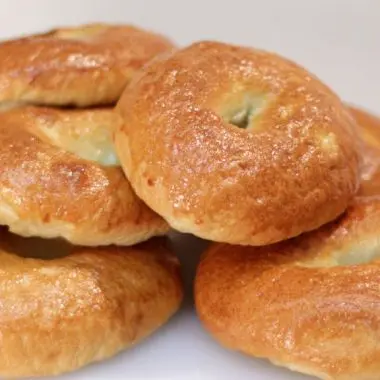 Stack of homemade bagels on a white cutting board
