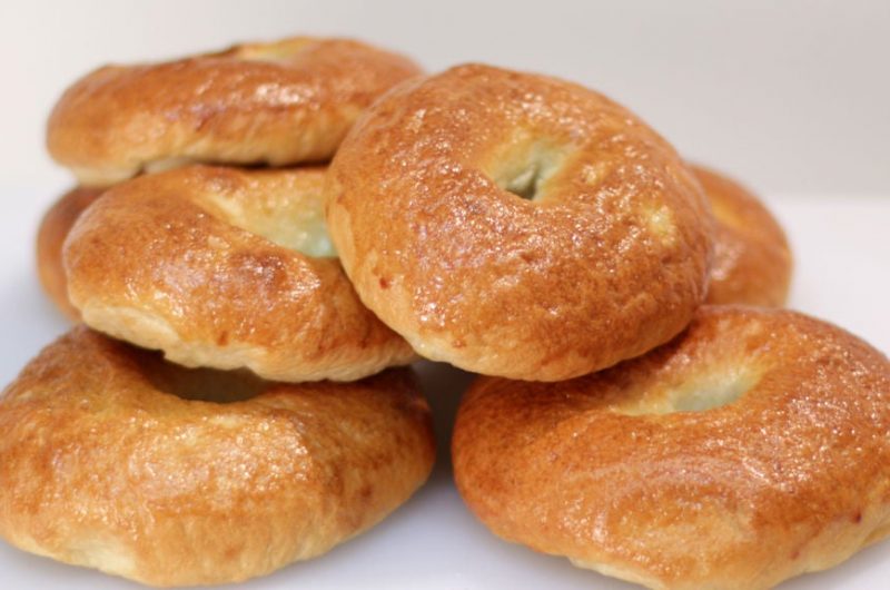 Stack of homemade bagels on a white cutting board