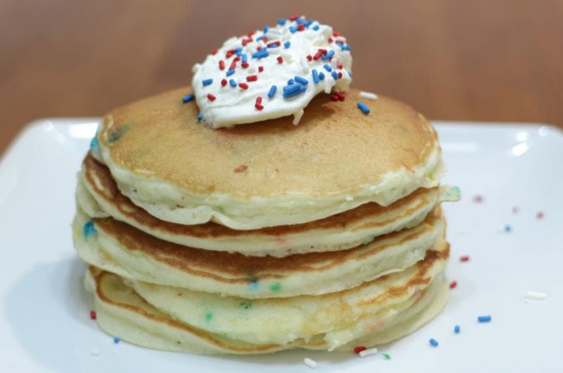 funfetti cake mix pancakes stacked on a white plate on a wooden table