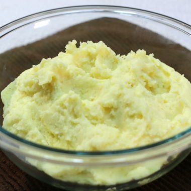 creamy mashed potatoes in a glass bowl on a brown towel