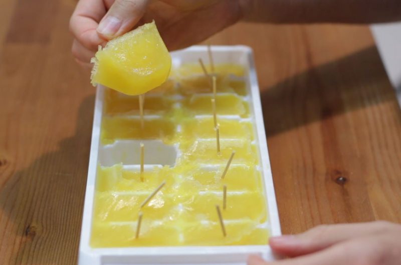 ice cube tray popsicles with toothpicks on top of wooden table