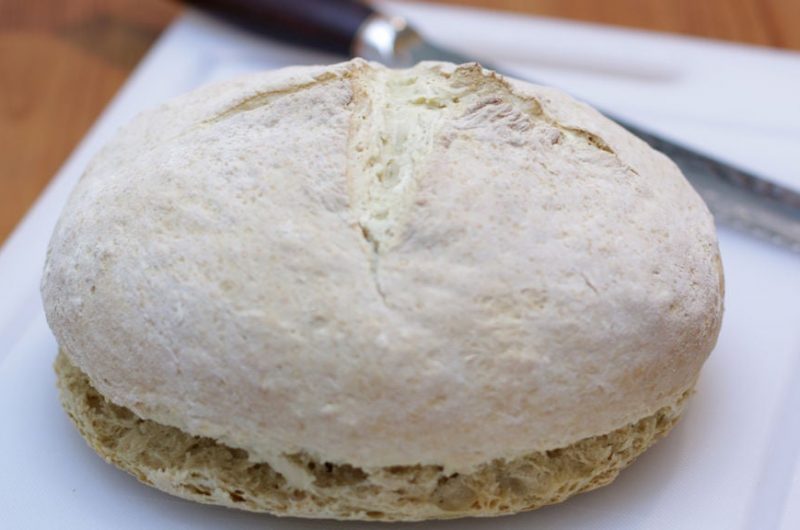 Soda bread on a white cutting board with a knife