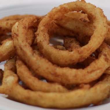 a pile of crispy onion rings on a white plate