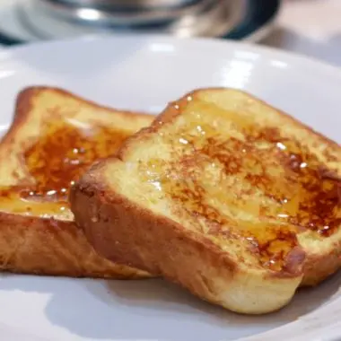 2 slices of French toast on a white plate on a table.