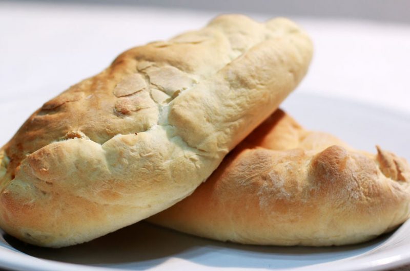 easy calzones piled on a white plate on a table.