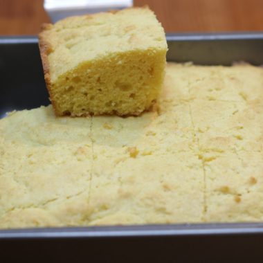 moist cornbread in a square metal pan on a wooden table