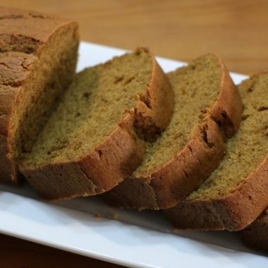 Sliced pumpkin bread on a white plate on a wooden table