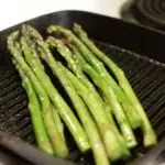 Grilled asparagus in a grill pan on a stove