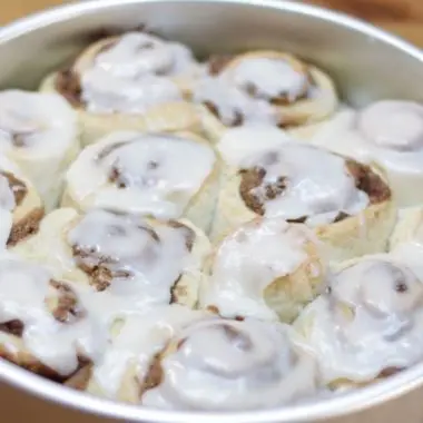 Easy cinnamon rolls without yeast topped with a glaze in a round silver cake pan