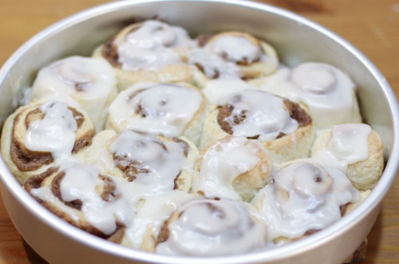 Easy cinnamon rolls without yeast topped with a glaze in a round silver cake pan