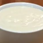 easy homemade vanilla pudding in a white bowl on a wooden table.