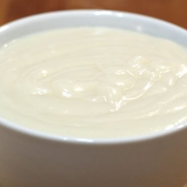 easy homemade vanilla pudding in a white bowl on a wooden table.