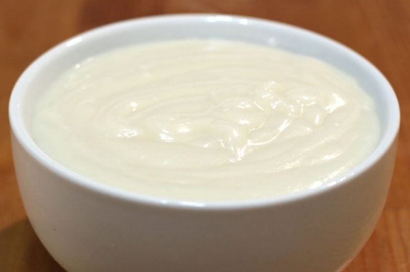 easy homemade vanilla pudding in a white bowl on a wooden table.
