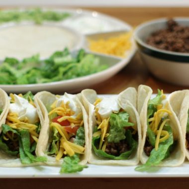 Ground beef tacos on a white plate on a wooden table