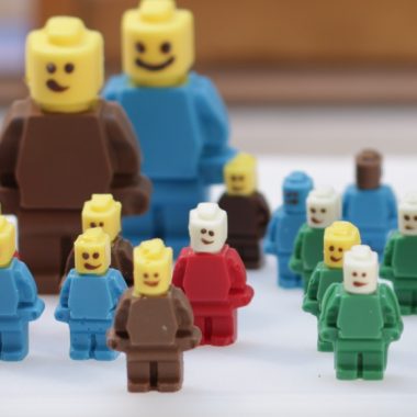 Several chocolate lego figures on a white table.