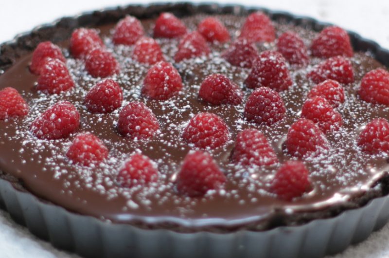 Chocolate raspberry tart on a white table
