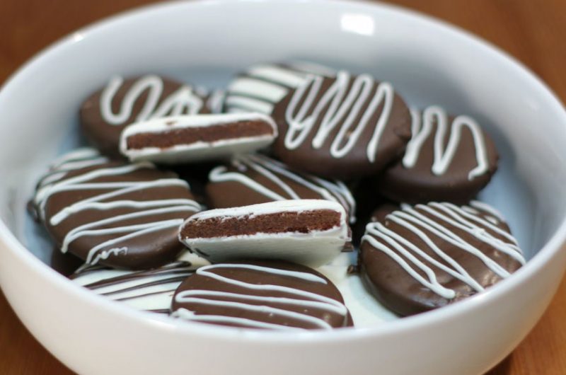 Chocolate thin mint cookies in a white bowl on a wooden table.