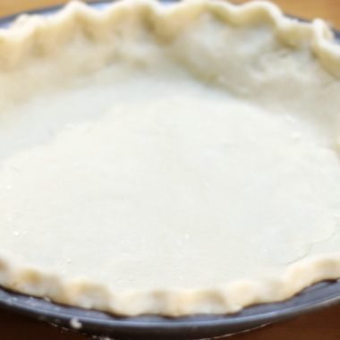 easy homemade perfect pie crust in metal pie plate on wooden table.
