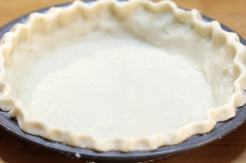 easy homemade perfect pie crust in metal pie plate on wooden table.