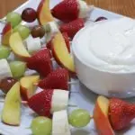 Easy homemade fruit dip in a bowl on a plate with fruit kebabs