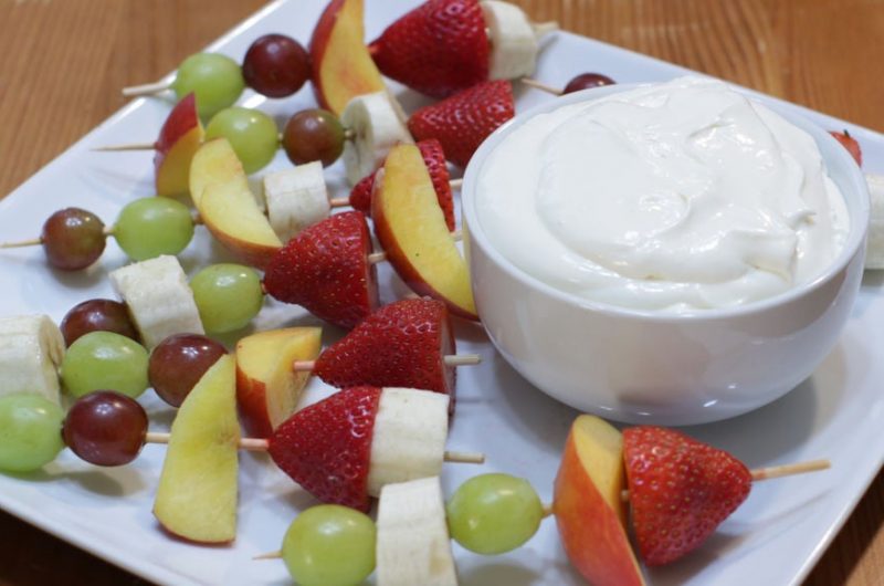 Easy homemade fruit dip in a bowl on a plate with fruit kebabs